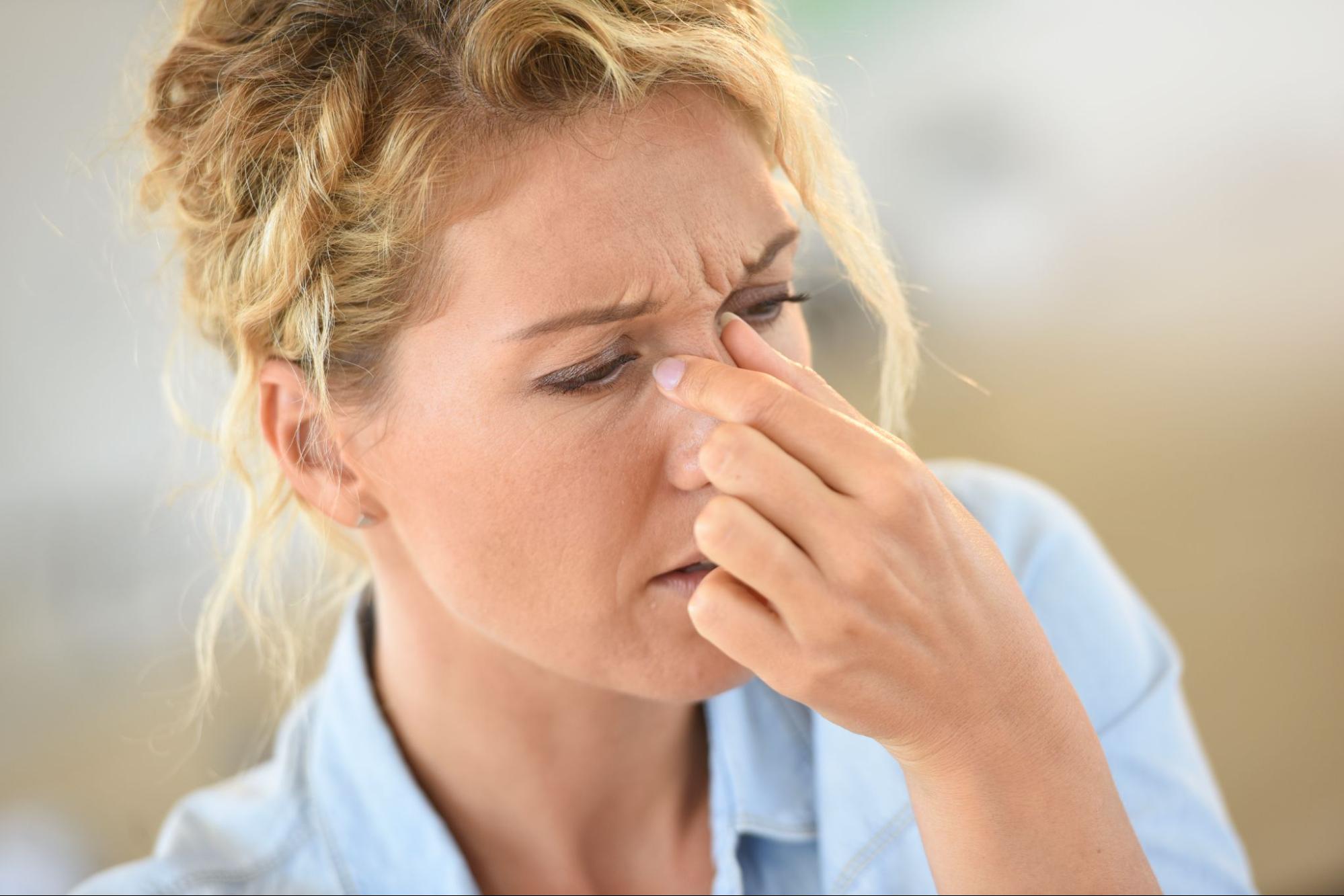 A woman pinching her nose in pain